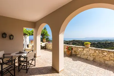 an outdoor patio with an archway and a stone wall at Villa Ariadne in Stalos