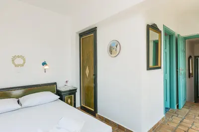 a bedroom with a white bed and two doors at Villa Ariadne in Stalos