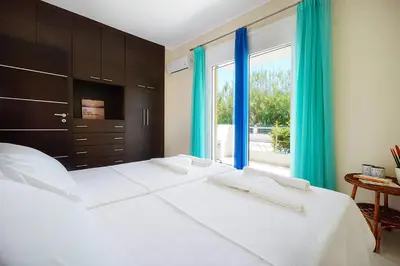 a bedroom with a large white bed with blue curtains at Geas House Thalassa in Kolymvari