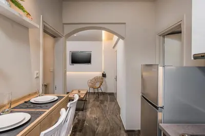 a kitchen with a table with white chairs and a refrigerator at Sun Ray Luxury Apartments in Agia Marina Nea Kydonias