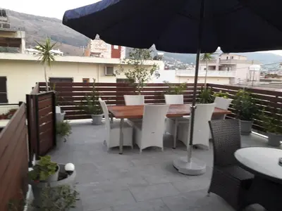 a patio with a table and chairs and an umbrella at Parthenon Hotel in Souda