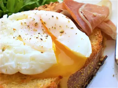 a sandwich with eggs and ham on a white plate at Tree of Life Art Hotel in Agia Marina Nea Kydonias