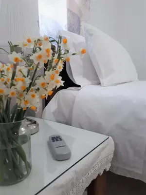 a vase of flowers on a table next to a bed at Eva's House in Kissamos