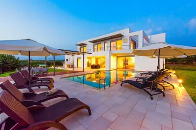 a villa with a swimming pool with chairs and umbrellas at Luxury Villa Stella with private swimming pool in Tersanas
