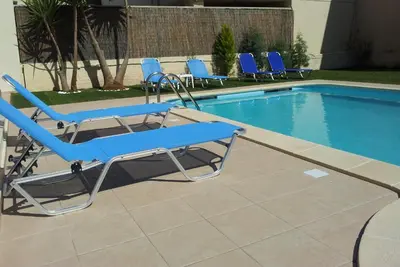 a group of blue lounge chairs next to a swimming pool at Nicolas Studios & Apartments in Agia Marina Nea Kydonias