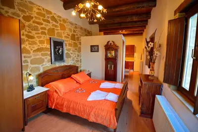 a bedroom with a bed with orange sheets and a stone wall at Maria Villas in Kissamos