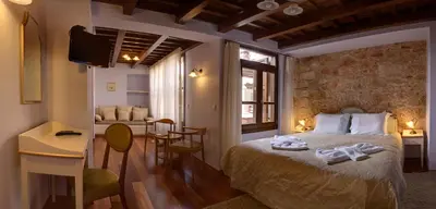 a bedroom with a bed and a table and a chair at Palazzo Duca in Chania Town