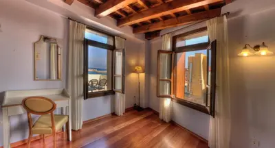 a hallway with windows and a chair and a table at Palazzo Duca in Chania Town