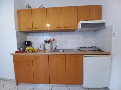 a small kitchen with wooden cabinets and a sink at Babis Apartments in Plataniás