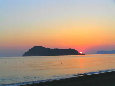 a sunset on the beach with a mountain in the background at Katerina Seaside Studios in Plataniás