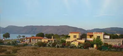 a group of houses in a field with mountains in the background at Drapanias BeachFront Apartments - Marinakis in Kissamos