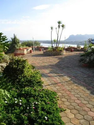a cobblestone walkway with bushes and palm trees at Theodosia Studios in Kalathas