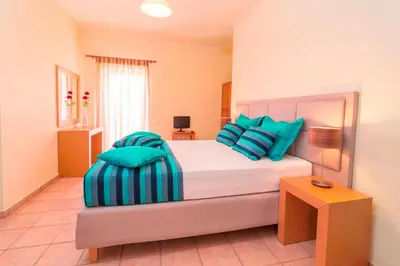 a bedroom with a large bed with blue pillows at Oreia in Palaiochóra
