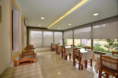 a dining room with tables and chairs and windows at Hotel Aghas Paleochora in Palaiochóra