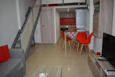 a living room with a couch and a table with red chairs at Rodoula Luxury Αpartment 3 in Chania Town