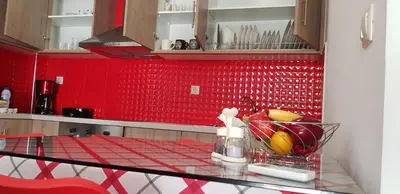 a red tiled kitchen with a glass table at Rodoula Luxury Αpartment 4 in Chania Town