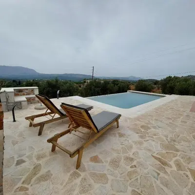 a patio with two chairs and a swimming pool at Villa Vendema in Arménoi