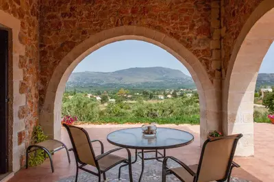 a patio with an archway with a table and chairs at Villa Vendema in Arménoi