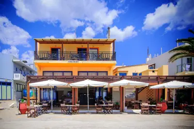 a building with tables and chairs and umbrellas at Scorpios Family Rooms in Palaiochóra