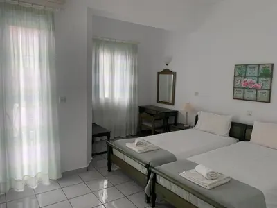 a bedroom with two beds and a table and a mirror at Astra Hotel Apartments in Kato Daratso