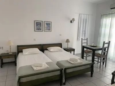 a bedroom with two beds and a table and chairs at Astra Hotel Apartments in Kato Daratso