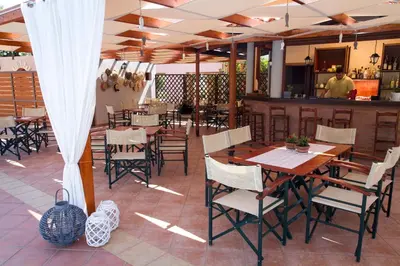 a restaurant with tables and chairs and a bar at Hotel Peli in Kissamos