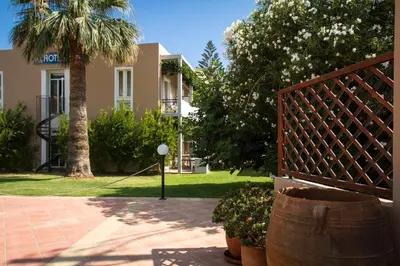a fence in front of a house with a palm tree at Hotel Peli in Kissamos