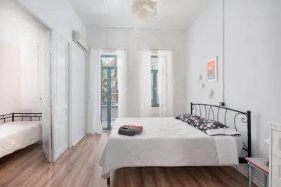 a white bedroom with a bed and a window at Lilian's House in Chania Town