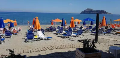 a beach with people sitting in chairs and umbrellas at Melina Beach in Plataniás