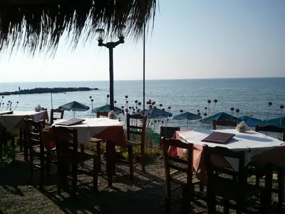 a group of tables on the beach with the ocean at Angelica Studios and Apartments in Agia Marina Nea Kydonias
