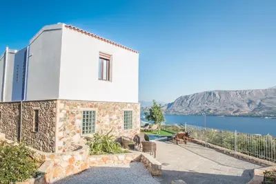 a stone house with a view of the water at Istros Villas - with Pools, BBQ & Heated Spa Whirlpools, By ThinkVilla in Korakiaí