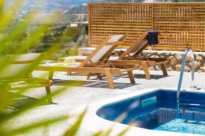 a couple of chairs and a swimming pool at Istros Villas - with Pools, BBQ & Heated Spa Whirlpools, By ThinkVilla in Korakiaí