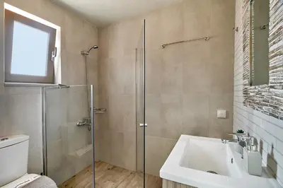 a bathroom with a glass shower and a sink at Lydia's Apartments in Kissamos