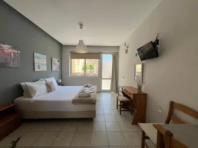 a bedroom with a bed and a television in it at Artemis Rooms two steps by the sea in Plataniás