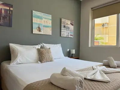 a bedroom with a large white bed with a window at Artemis Rooms two steps by the sea in Plataniás