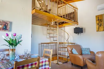 a living room with a table and a spiral staircase at Olive Villas in Kría Vrísi