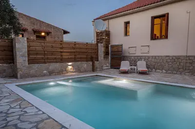 a swimming pool with two chairs and a house at Olive Villas in Kría Vrísi