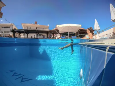 a woman is swimming in a swimming pool at Dias Hotel Apartments in Agia Marina Nea Kydonias