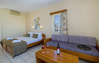 a hotel room with a bed and a couch and wine glasses at Dias Hotel Apartments in Agia Marina Nea Kydonias