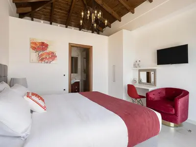 a bedroom with a white bed and a red chair at Villa Aloni in Kissamos