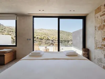 a bedroom with a large bed with a large window at Monastery Estate Retreat in Sougia