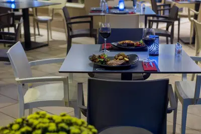 a table with two plates of food and two glasses of wine at Oscar Suites & Village in Agia Marina Nea Kydonias