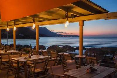 a restaurant with tables and chairs in front of the ocean at Maria Beach Hotel in Kissamos