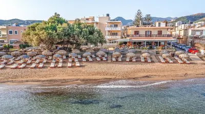 a group of chairs on a beach next to the water at Maria Beach Hotel in Kissamos