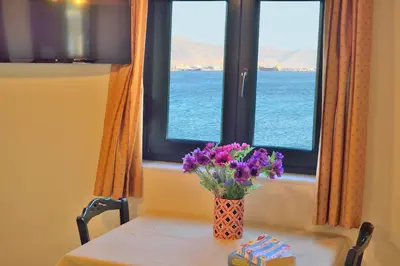 a vase of purple flowers on a table in front of a window at Maria Beach Hotel in Kissamos