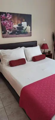 a large white bed with two red pillows on it at Modern Apartment Chania Center in Chania Town