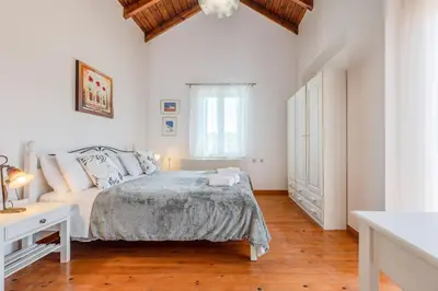 a white bedroom with a bed and a window at Helianthos Villas in Douliana