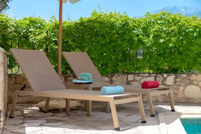 two chairs with hats on them sitting next to a pool at Helianthos Villas in Douliana