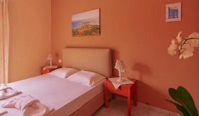 a bedroom with orange walls and a bed with two tables at Oriental Bay in Palaiochóra