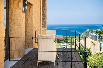 a balcony with two chairs and a table at Villa Emilia front sea in Kalathas